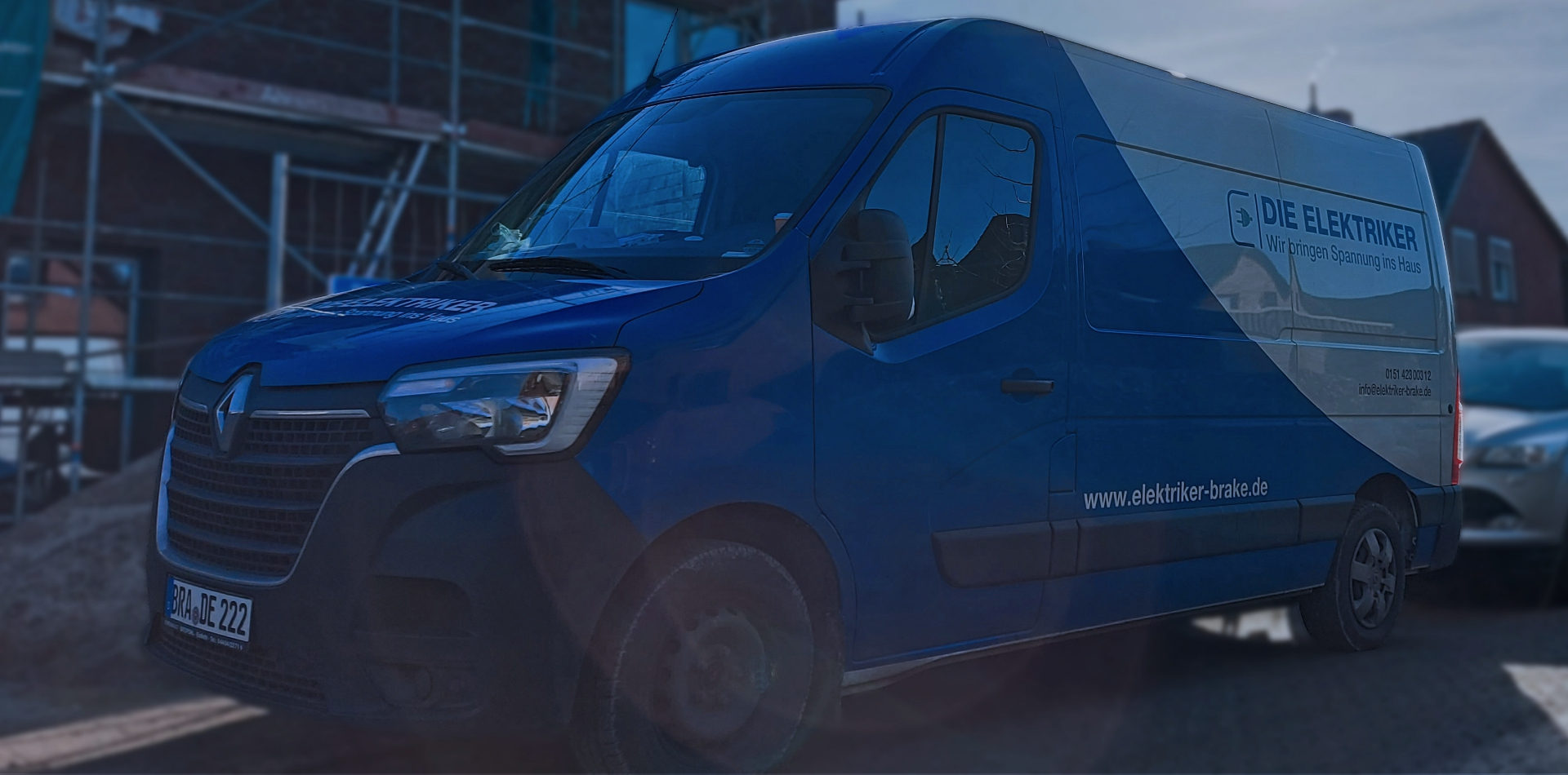 Blau-weißer Transporter von Die Elektriker aus Brake vor einer Baustelle