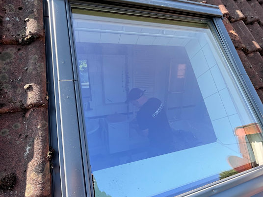 Ein neues Dachfenster mit alten Dachziegeln drumherum und Mitarbeiter im Zimmer