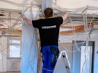 Elektroinstallation durch einen Mitarbeiter auf Leiter in einem Altbau